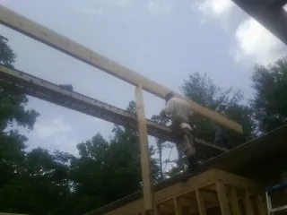 Carpenter setting a ridge beam over a new addition frame — Ice Dam Removal by Roofing Brothers in Ackley