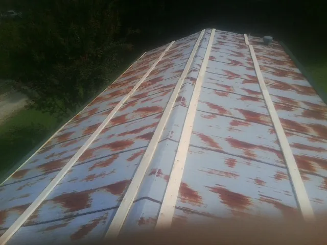 Rusted metal roof panels with new wood purlins before replacement — Storm Damage Roof Repair in Ackley by Roofing Brothers