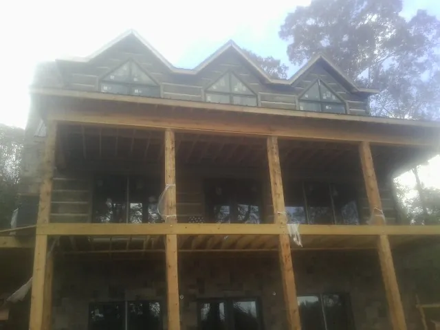 Dormers and porch framing on a large log home under construction — Roof Coating work by our crew in Ackley