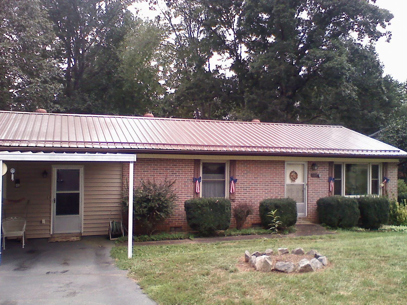 Bronze metal roof and carport on a brick ranch home — Roof Repair work by our crew in Ackley